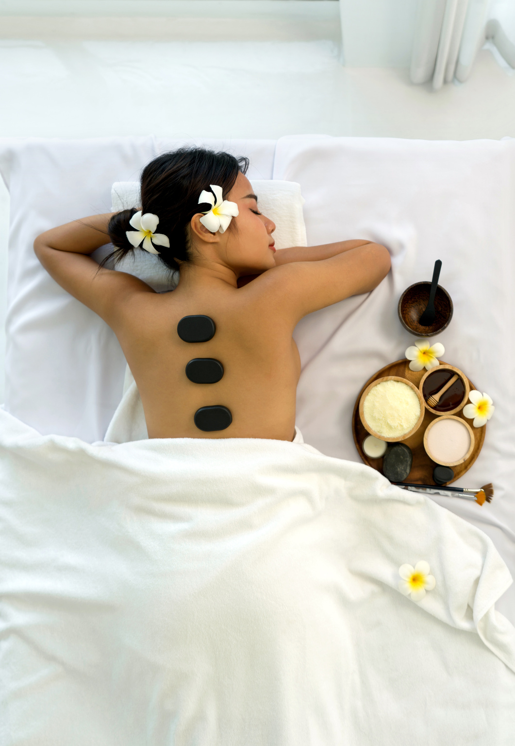 Woman getting spa hot stones massage. Lying on a massage table, relaxing with eyes closed.  Spa Thai therapy treatment aromatherapy for beauty body. Spa beauty massage healthy wellness. Top View